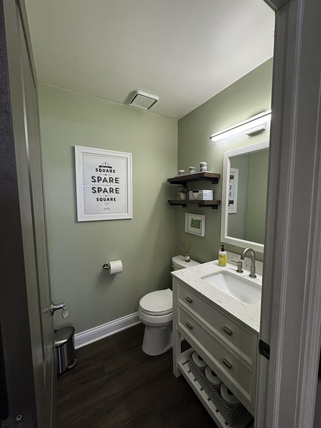 bathroom with toilet, wood finished floors, vanity, and baseboards