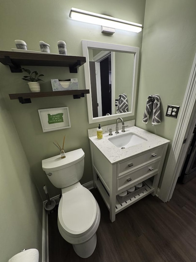 half bath with toilet, wood finished floors, and vanity