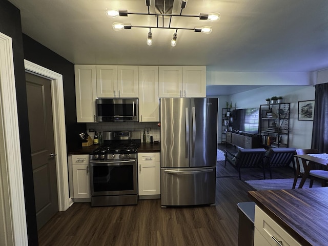 kitchen featuring appliances with stainless steel finishes, dark countertops, dark wood finished floors, and white cabinetry