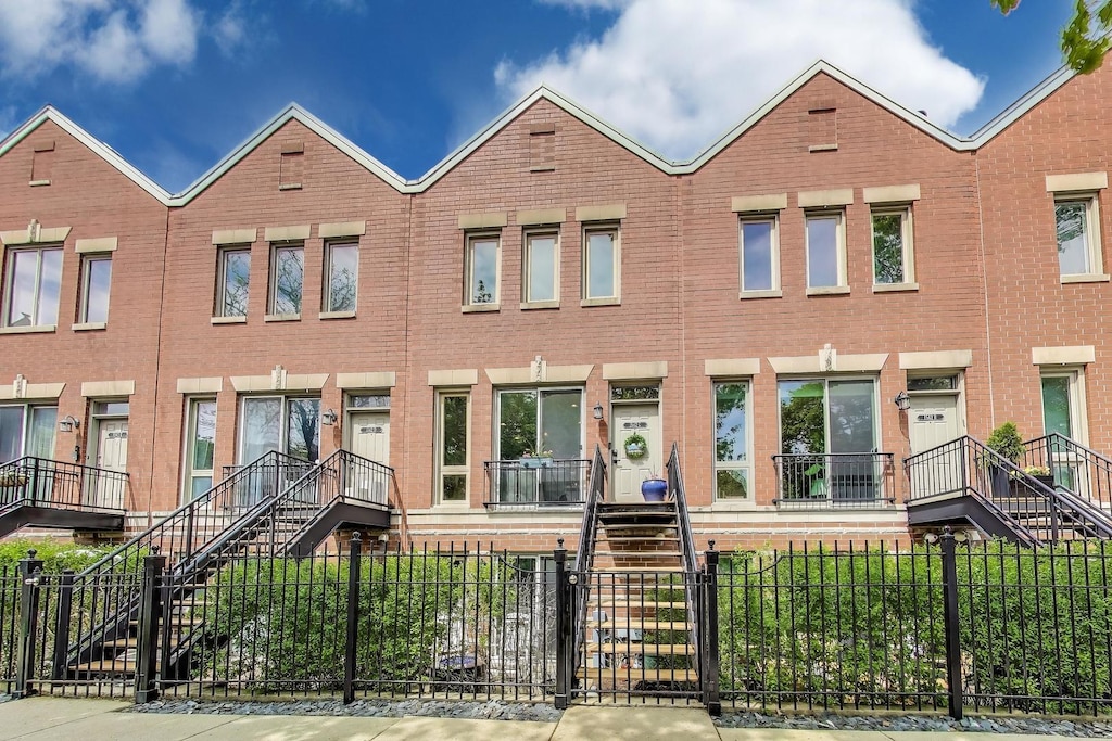 1542 W School St Unit C, Chicago, IL 60657 - view of front facade with stairway, brick siding, and a fenced front yard