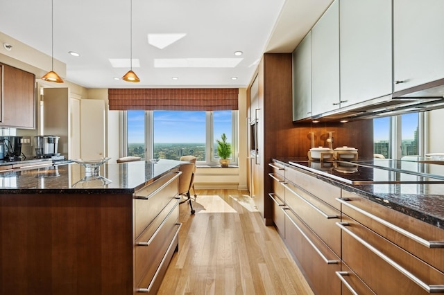 132 E Delaware Pl Unit 4901, Chicago, IL 60611 - kitchen featuring black electric cooktop, light wood-type flooring, a skylight, dark stone countertops, and pendant lighting