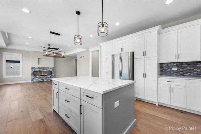 kitchen with freestanding refrigerator, tasteful backsplash, a fireplace, a center island, and white cabinets