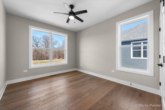 unfurnished room with baseboards, dark wood-type flooring, and ceiling fan