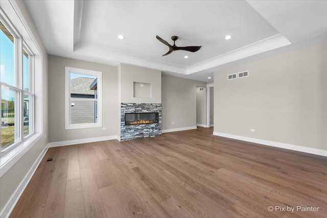 unfurnished living room with a raised ceiling, wood finished floors, baseboards, ceiling fan, and recessed lighting