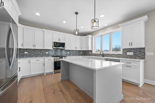 kitchen featuring stainless steel appliances, light wood-style floors, tasteful backsplash, white cabinets, and a kitchen island