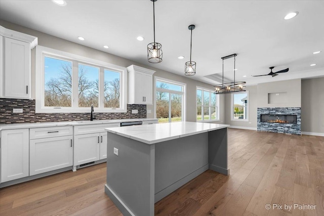 kitchen with tasteful backsplash, white cabinets, a center island, recessed lighting, and a fireplace