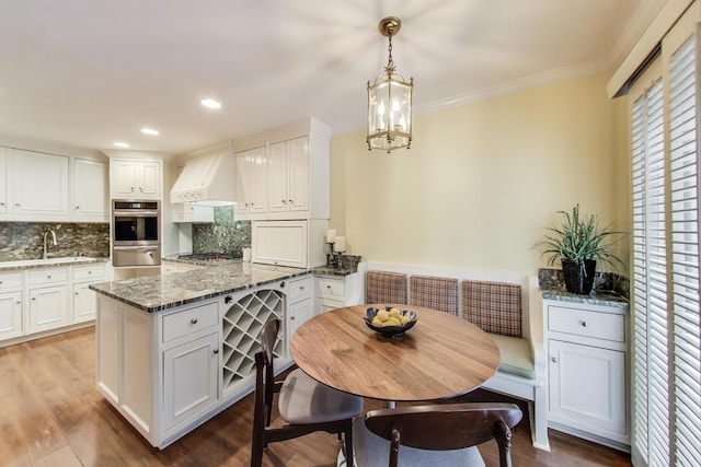 215 W Concord Ln, Chicago, IL 60614 - kitchen featuring custom range hood, white cabinetry, appliances with stainless steel finishes, tasteful backsplash, and a peninsula