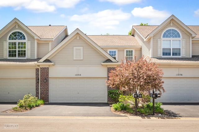 view of front facade featuring brick siding, driveway, a garage, and a shingled roof