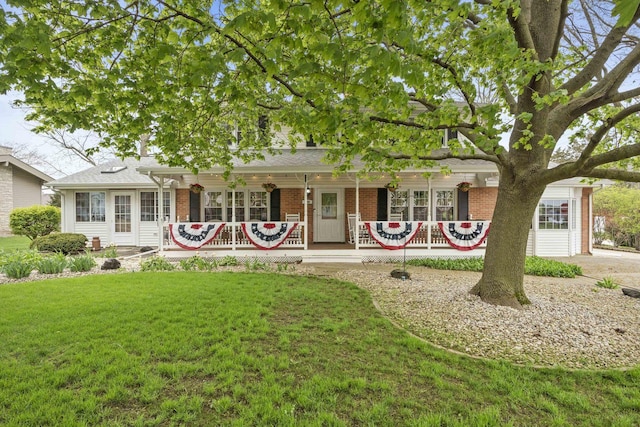 back of house featuring brick siding, covered porch, and a lawn