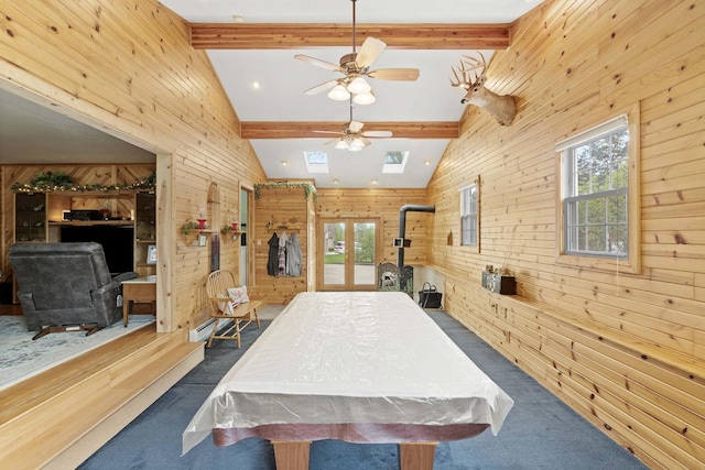 rec room with a wood stove, wooden walls, pool table, dark carpet, and a ceiling fan