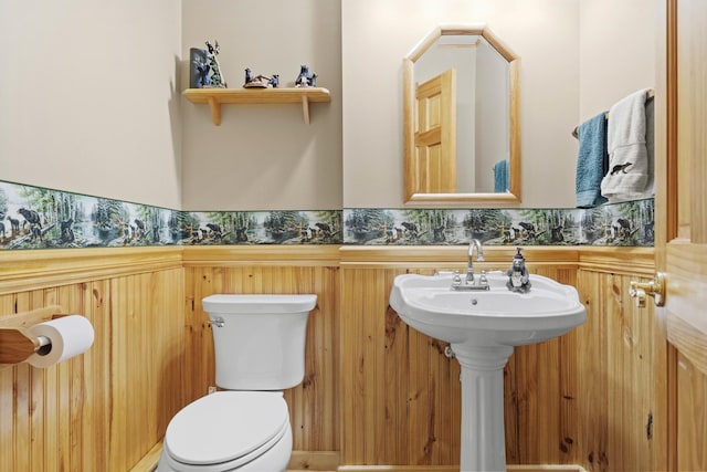 bathroom featuring toilet and a wainscoted wall