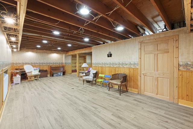 living area featuring wood finished floors, wooden walls, and a wainscoted wall