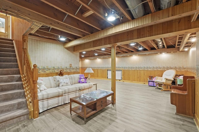 finished basement featuring stairway, wood finished floors, wainscoting, and wooden walls