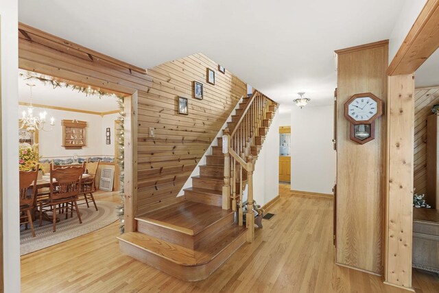 stairway with a chandelier, wood walls, and wood finished floors