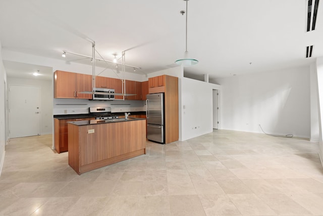 kitchen featuring stainless steel appliances, dark countertops, open floor plan, a kitchen island, and brown cabinetry