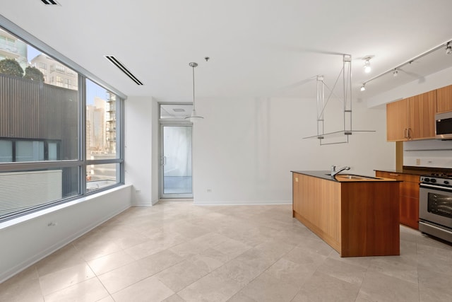 kitchen featuring appliances with stainless steel finishes, modern cabinets, a sink, a kitchen island with sink, and dark countertops
