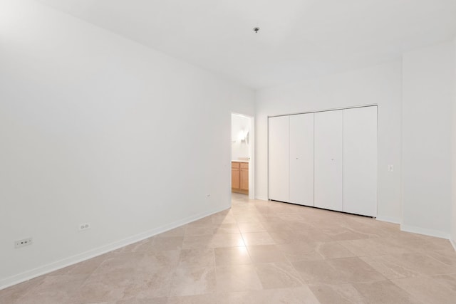 unfurnished bedroom featuring baseboards, a closet, and ensuite bathroom