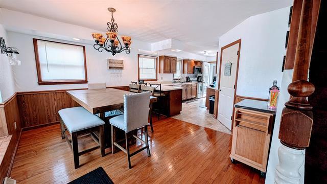 dining room featuring a chandelier, light wood-style floors, and wainscoting