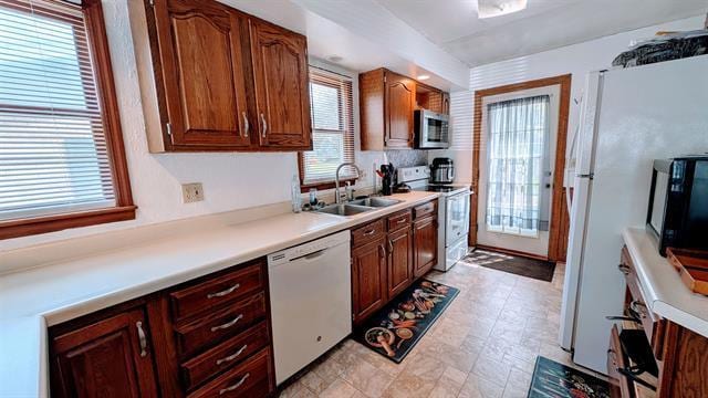 kitchen featuring white appliances, a sink, and light countertops