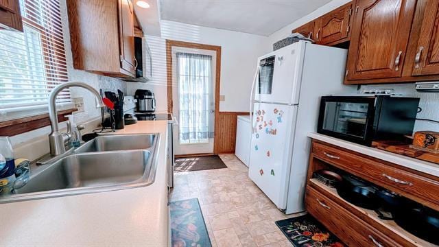 kitchen featuring a sink, wainscoting, freestanding refrigerator, electric stove, and light countertops