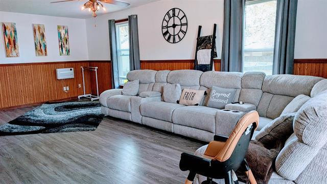 living area with wainscoting, wood walls, a ceiling fan, and wood finished floors