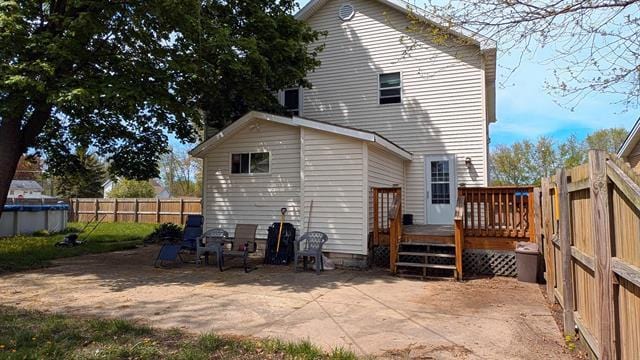 back of property with a deck, a fenced backyard, and a patio