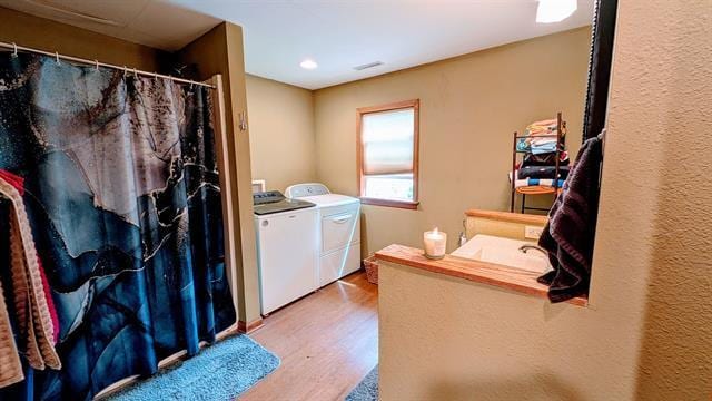 laundry area featuring washing machine and clothes dryer, wood finished floors, and recessed lighting