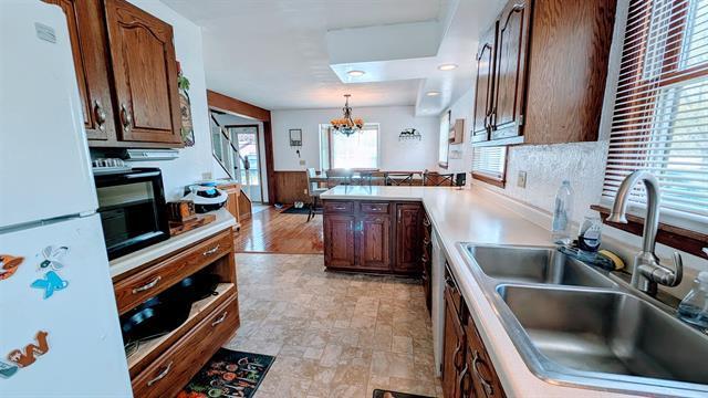 kitchen featuring freestanding refrigerator, a sink, a chandelier, a peninsula, and pendant lighting