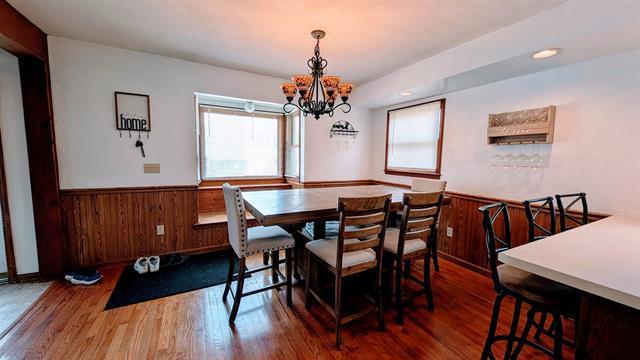 dining area with a chandelier, a wainscoted wall, wooden walls, and wood finished floors
