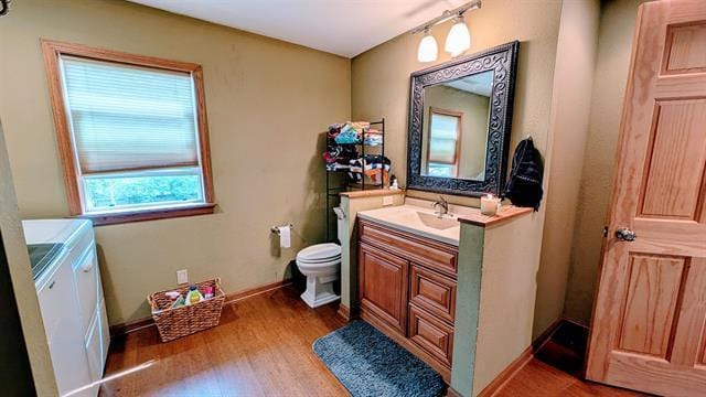 bathroom with washing machine and clothes dryer, vanity, wood finished floors, toilet, and baseboards