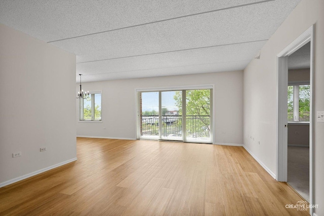 100 N Gary Ave Unit 308, Wheaton, IL 60187 - empty room with a chandelier, light wood-type flooring, a textured ceiling, and baseboards