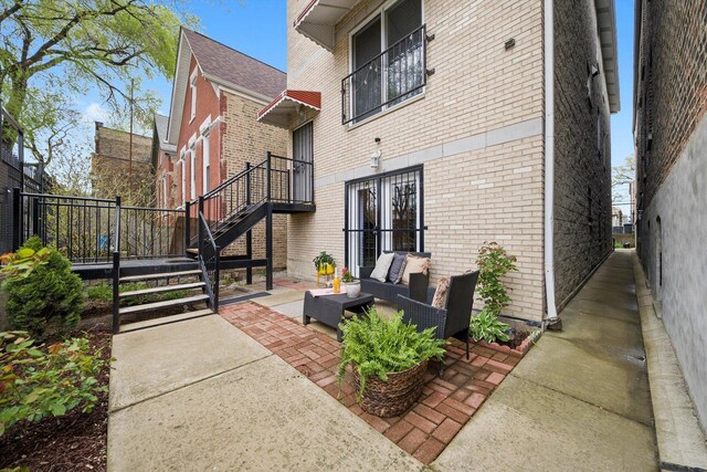 view of home's exterior with brick siding, outdoor lounge area, a patio area, and stairway