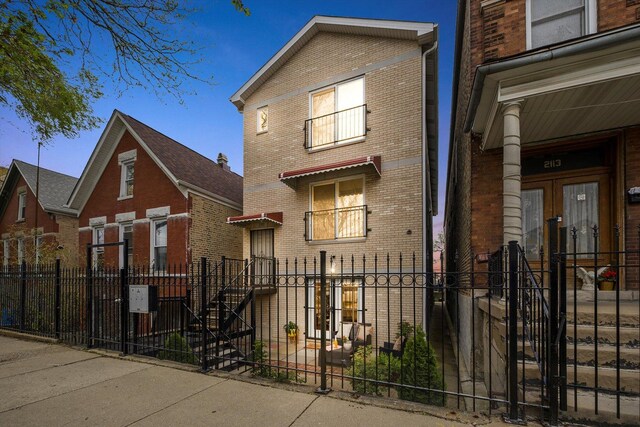 view of front facade featuring brick siding, a fenced front yard, and french doors