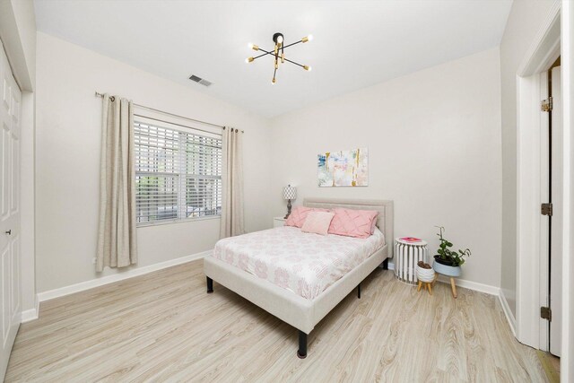 bedroom featuring a chandelier, light wood-style floors, and baseboards