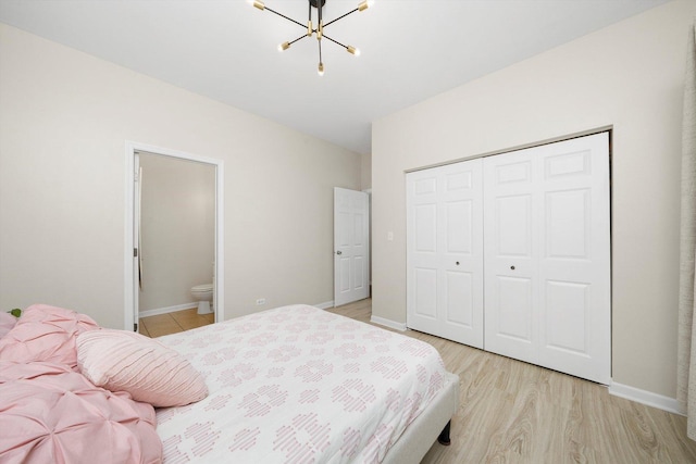 bedroom with a chandelier, a closet, light wood-style floors, and baseboards