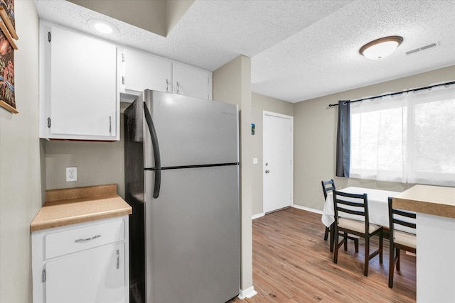 1109 Laura Dr Unit 9, Champaign, IL 61822 - kitchen featuring freestanding refrigerator, white cabinetry, light wood-style flooring, baseboards, and a textured ceiling