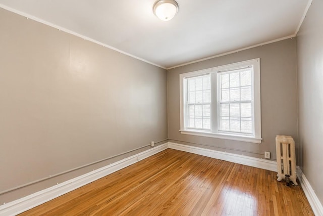unfurnished room featuring radiator, crown molding, light wood-type flooring, and baseboards