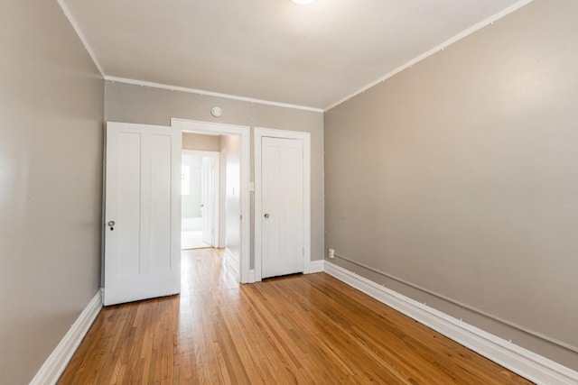 spare room with light wood-style floors, baseboards, and crown molding