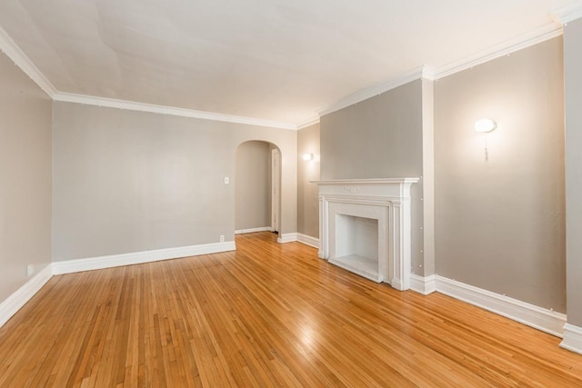 unfurnished living room featuring arched walkways, light wood finished floors, baseboards, ornamental molding, and a fireplace