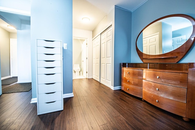 bedroom featuring dark wood-style flooring, baseboards, and a closet