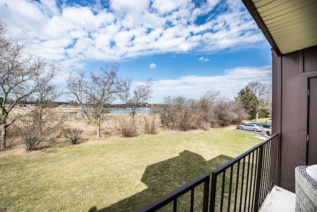 view of green lawn featuring a water view and a balcony