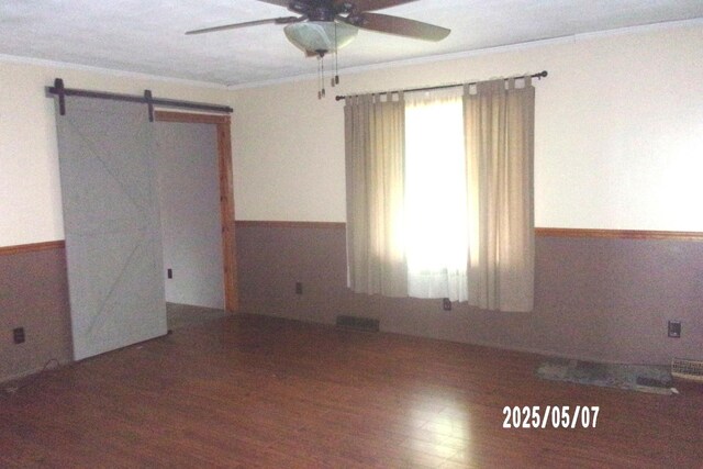 704 E Sycamore St, Watseka, IL 60970 - spare room with ceiling fan, crown molding, wood finished floors, and a barn door