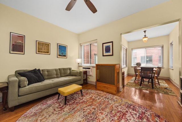 living room with hardwood / wood-style flooring, ceiling fan, and baseboards
