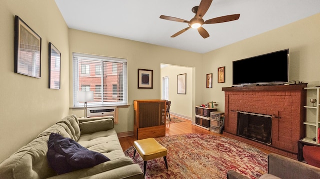 living area featuring ceiling fan, wood finished floors, a fireplace, and baseboards