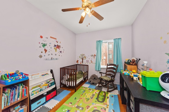 bedroom featuring wood finished floors, a ceiling fan, baseboards, and a nursery area