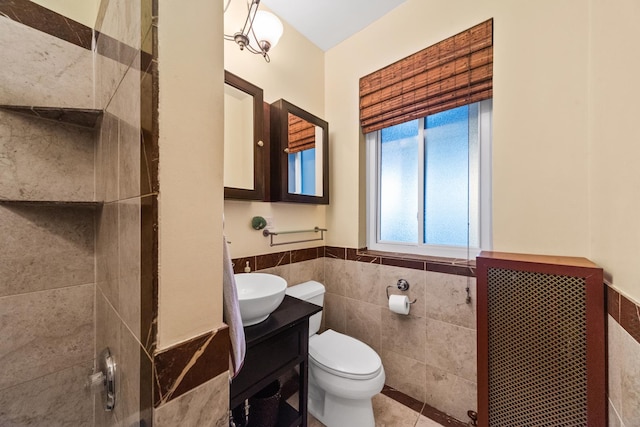 bathroom with tile walls, wainscoting, toilet, tile patterned flooring, and vanity