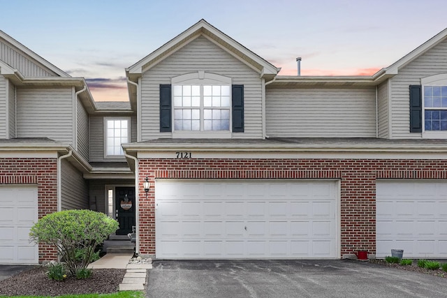 view of front of house featuring brick siding, an attached garage, and driveway