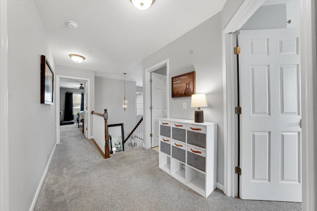 corridor featuring an upstairs landing, light carpet, and baseboards