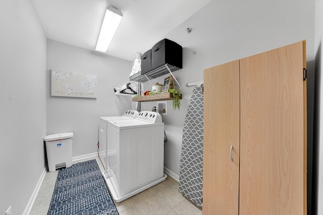 laundry area with independent washer and dryer, light tile patterned floors, and baseboards