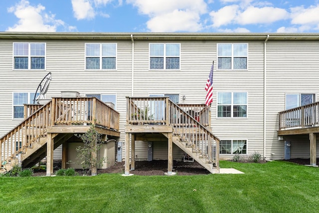 rear view of property featuring stairway, a lawn, and a wooden deck